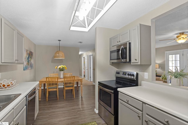 kitchen with gray cabinetry, light countertops, stainless steel appliances, wood finished floors, and a textured ceiling