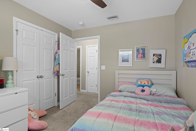 bedroom featuring light carpet, visible vents, a textured ceiling, and a closet