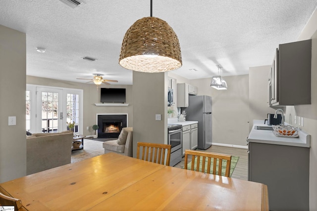 dining space featuring a textured ceiling, light wood-style floors, visible vents, and a lit fireplace