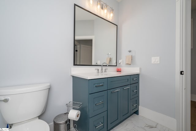 bathroom with vanity, toilet, baseboards, and marble finish floor