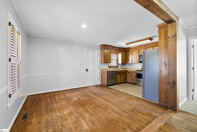 kitchen with visible vents, a sink, appliances with stainless steel finishes, light wood finished floors, and light countertops