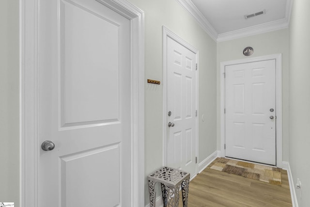 entryway with light wood-style flooring, baseboards, visible vents, and ornamental molding