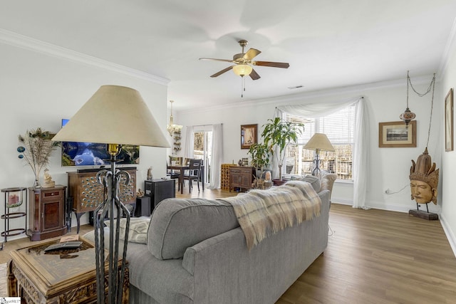 living area with a healthy amount of sunlight, baseboards, ornamental molding, and wood finished floors