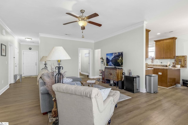 living room with ceiling fan, light wood-style floors, baseboards, and ornamental molding