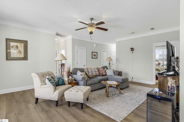 living area featuring ornamental molding, wood finished floors, visible vents, and baseboards