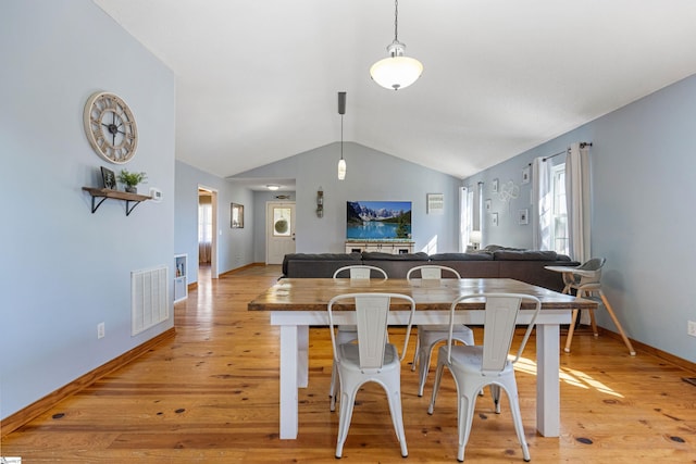 dining room featuring light wood finished floors, visible vents, baseboards, and vaulted ceiling