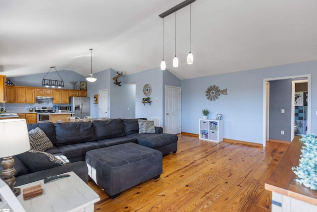 living area with lofted ceiling, light wood-style flooring, and baseboards