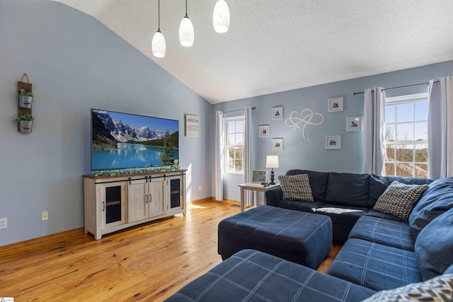 living room featuring light wood finished floors, a textured ceiling, and vaulted ceiling