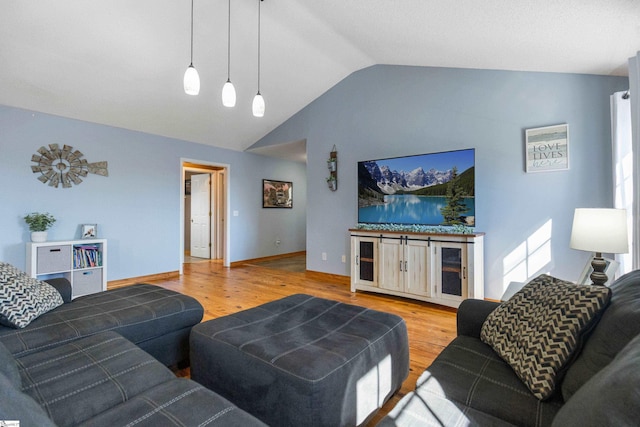 living area featuring vaulted ceiling, wood finished floors, and baseboards