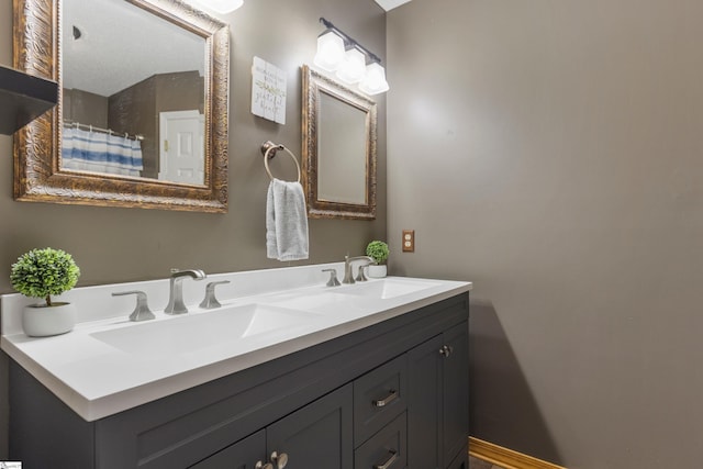 full bath with double vanity, baseboards, and a sink