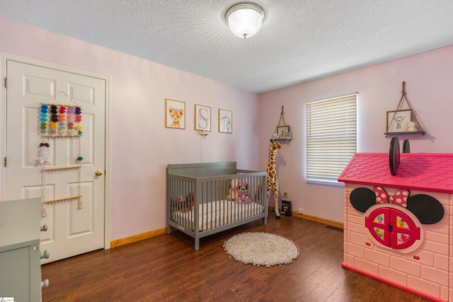 bedroom featuring wood finished floors, baseboards, and a textured ceiling