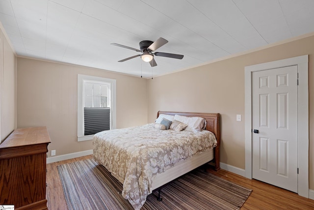 bedroom featuring a ceiling fan, baseboards, and wood finished floors