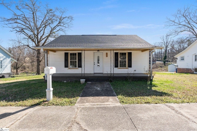 bungalow-style home with covered porch, a front yard, and a shingled roof