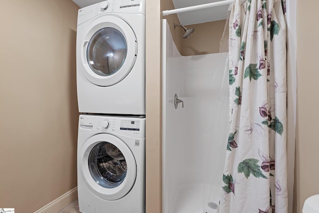 laundry area featuring laundry area, baseboards, and stacked washer / drying machine