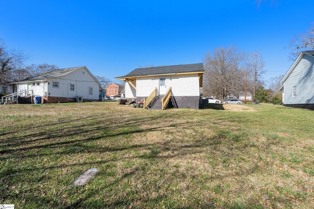 rear view of house featuring a lawn and entry steps