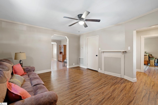 living area with baseboards, wood finished floors, visible vents, and arched walkways