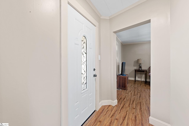 foyer entrance featuring light wood-type flooring, baseboards, and ornamental molding