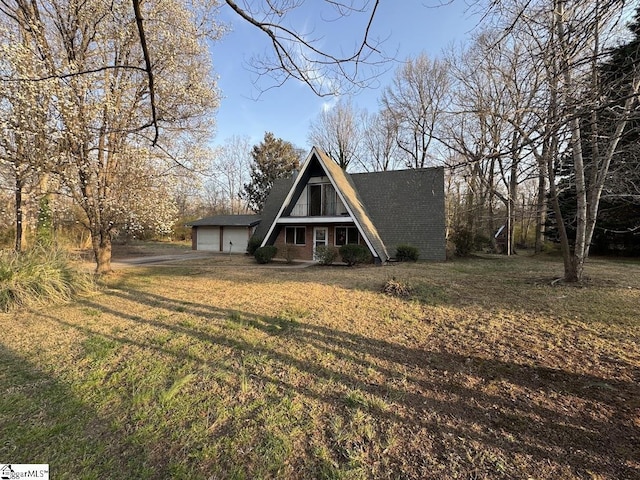 a-frame style home with brick siding, an attached garage, and a front lawn