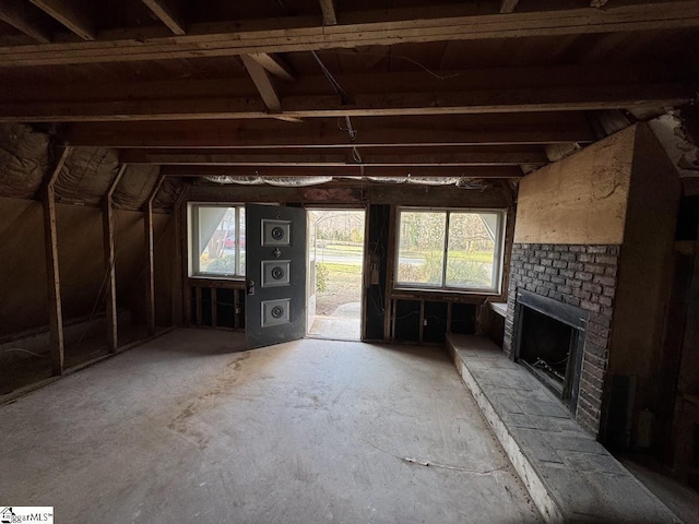 unfurnished living room with lofted ceiling and a brick fireplace