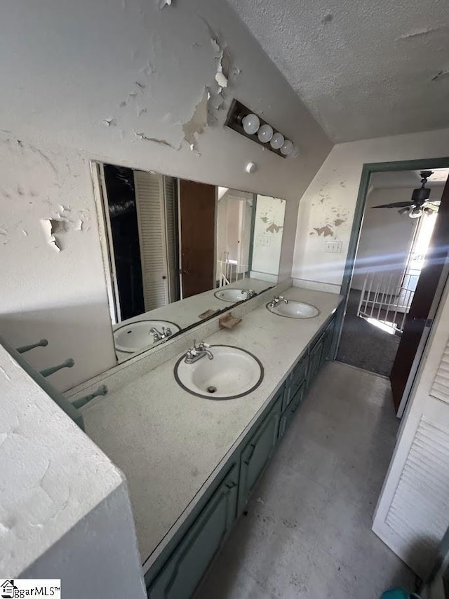 full bath featuring a textured ceiling, double vanity, and a sink