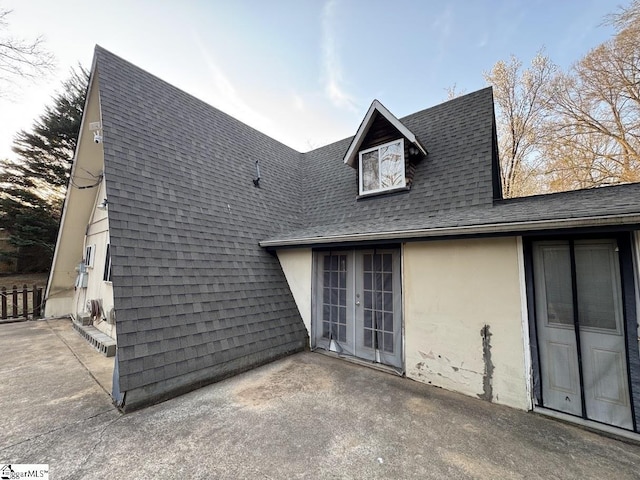 back of house with stucco siding, french doors, a shingled roof, and a patio