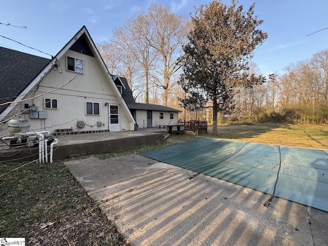 back of house with a yard, a patio, and a shingled roof