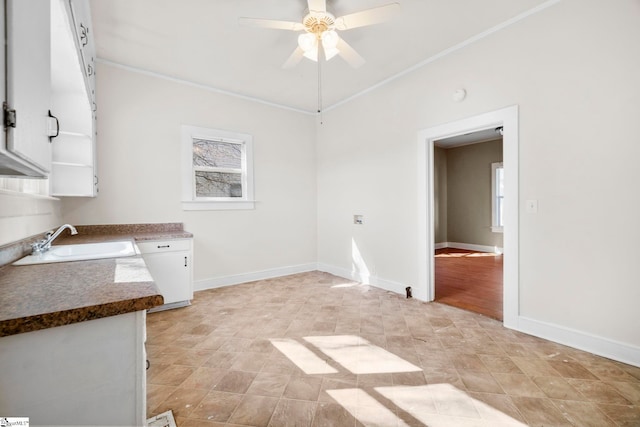 interior space with ceiling fan, ornamental molding, baseboards, and a sink