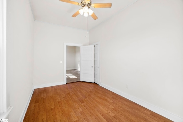 spare room with baseboards, light wood-style floors, and a ceiling fan