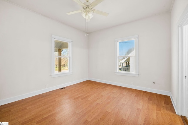 spare room featuring visible vents, baseboards, light wood-style floors, and a ceiling fan