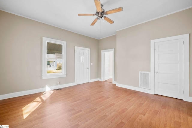 empty room with visible vents, ornamental molding, light wood-style floors, baseboards, and ceiling fan