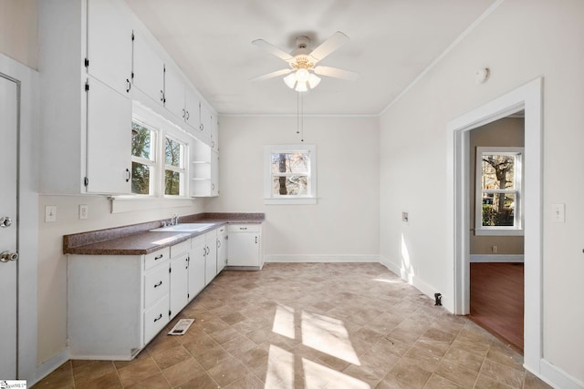 kitchen with a ceiling fan, a sink, dark countertops, white cabinetry, and baseboards