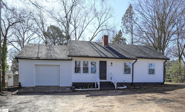 view of front of house with an attached garage, entry steps, roof with shingles, a chimney, and driveway