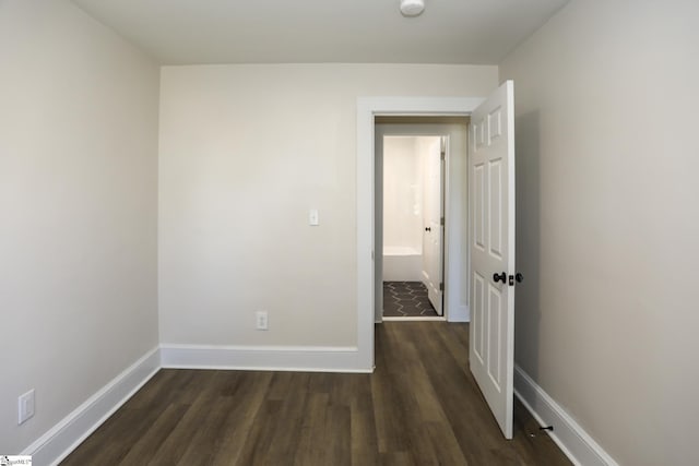 unfurnished room with baseboards and dark wood-type flooring