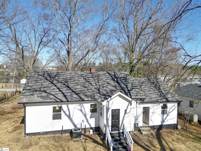 exterior space with central AC unit, a chimney, and a shingled roof