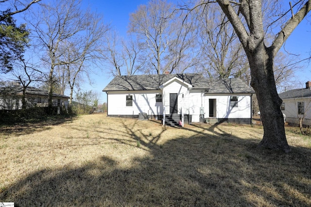 rear view of property featuring a yard and entry steps