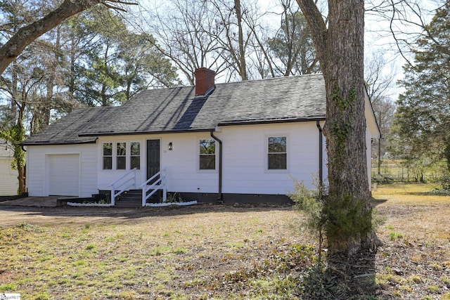 ranch-style home featuring a garage, a chimney, and a shingled roof