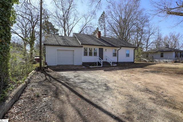 ranch-style house featuring entry steps, driveway, a chimney, and an attached garage