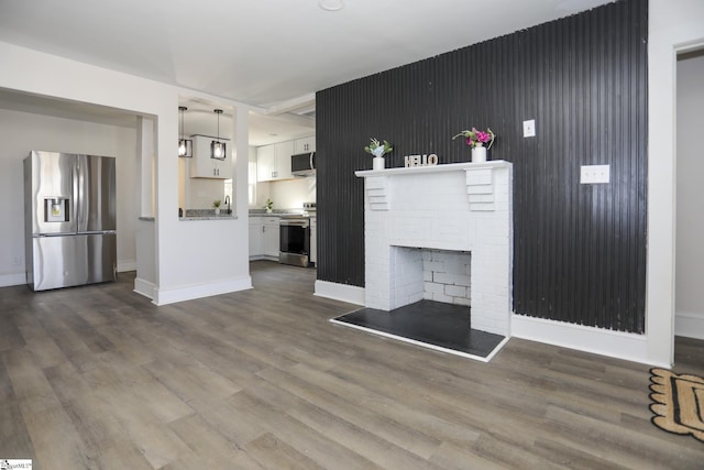 unfurnished living room with baseboards, dark wood finished floors, and a fireplace