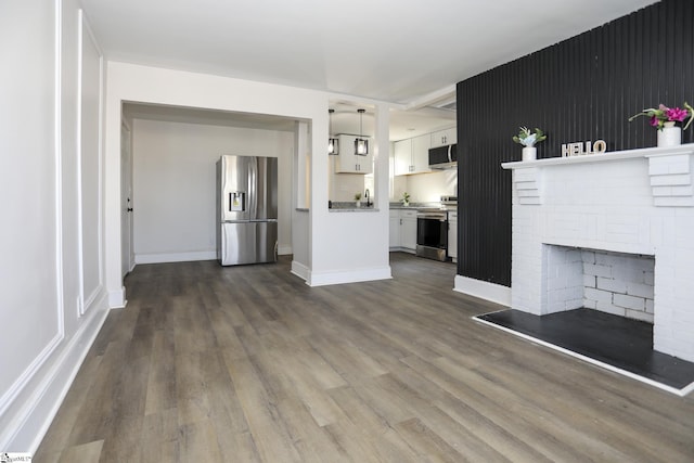 unfurnished living room featuring dark wood-type flooring, a fireplace, and baseboards