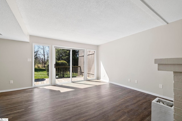 unfurnished living room with a stone fireplace, a textured ceiling, baseboards, and wood finished floors