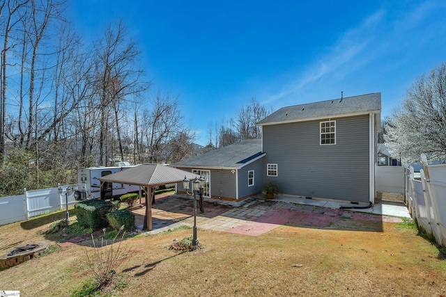 rear view of property featuring an attached carport, a fenced backyard, a gazebo, a patio area, and a lawn