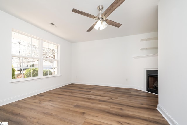 unfurnished living room featuring visible vents, a ceiling fan, wood finished floors, a fireplace, and baseboards