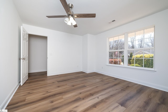 unfurnished room featuring wood finished floors, visible vents, and baseboards