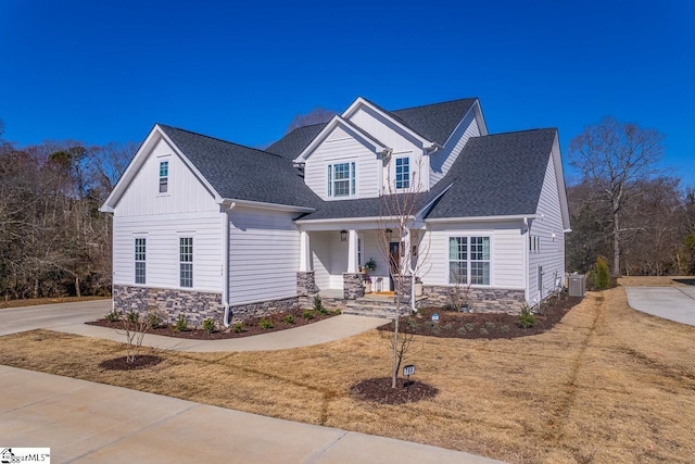 view of front of property featuring a porch, stone siding, central AC, and a shingled roof