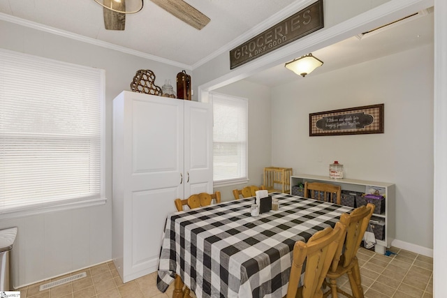 dining room with light tile patterned floors, visible vents, a ceiling fan, and crown molding