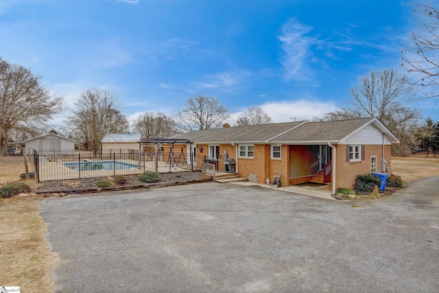 exterior space featuring a fenced in pool, fence, a chimney, a carport, and brick siding