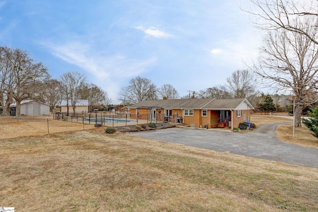 view of front of house with a front yard, fence, and a fenced in pool