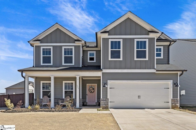 craftsman-style house with driveway, stone siding, covered porch, board and batten siding, and a garage