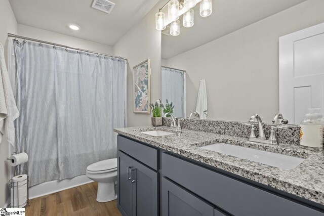 bathroom featuring toilet, wood finished floors, visible vents, and a sink