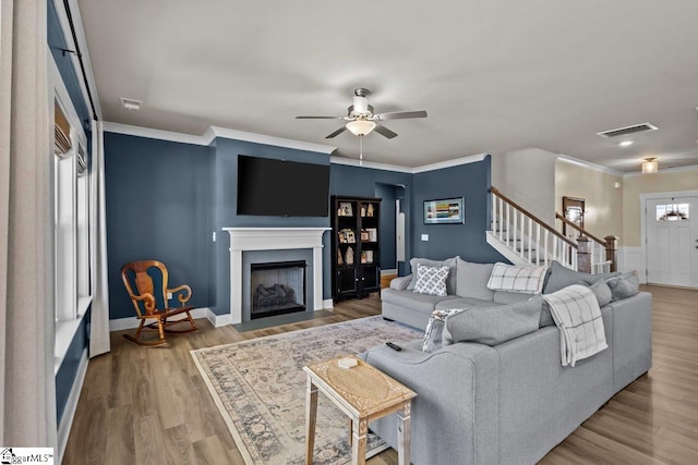 living room with visible vents, wood finished floors, stairway, crown molding, and ceiling fan